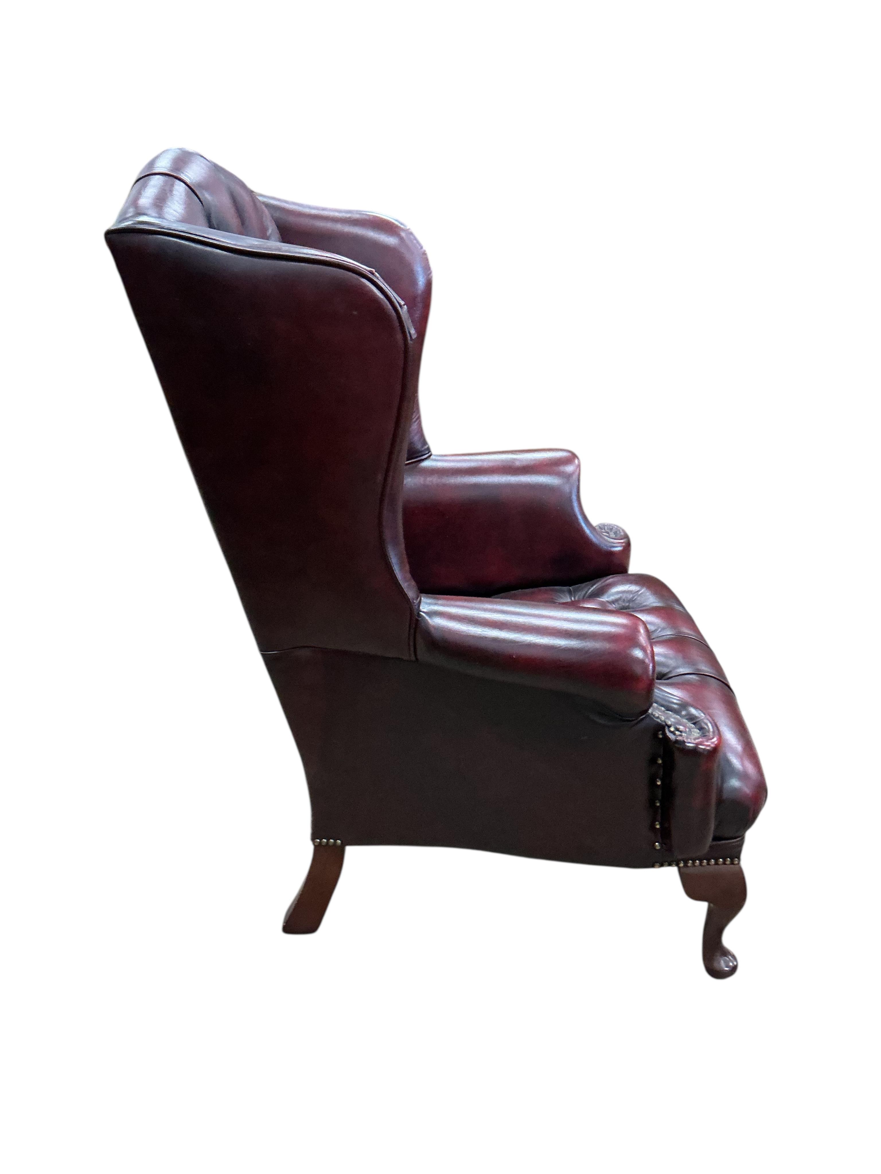A pair of reproduction buttoned burgundy leather wing armchairs, width 82cm, depth 70cm, height 104cm
